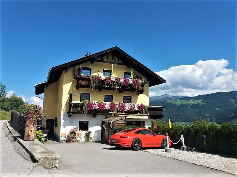 a red car parked in front of a building at Apart- Chalet GletscherGlück in Telfes im Stubai