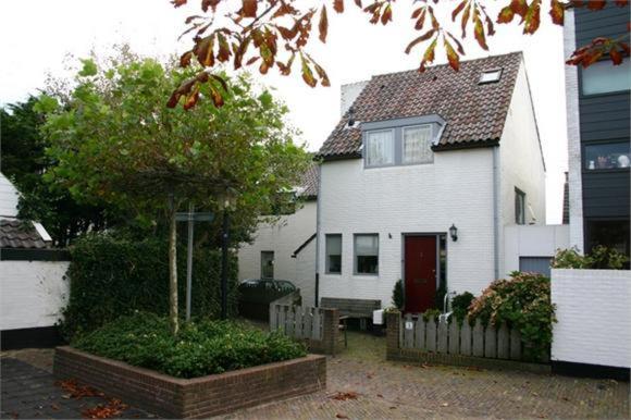una casa blanca con una puerta roja y un árbol en Continentaiz Appartement, en Zandvoort