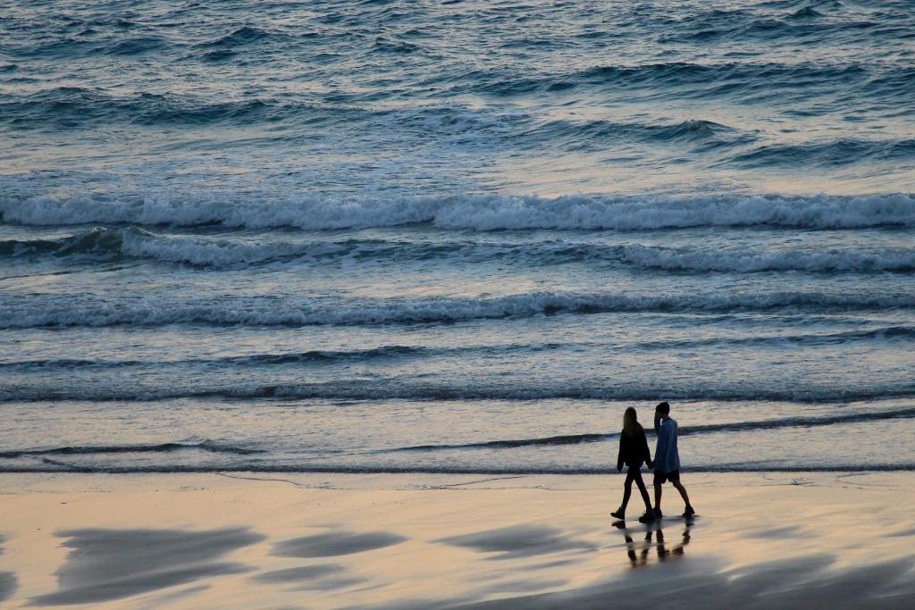 two people walking on the beach near the ocean at Watersmeet Hotel in Woolacombe