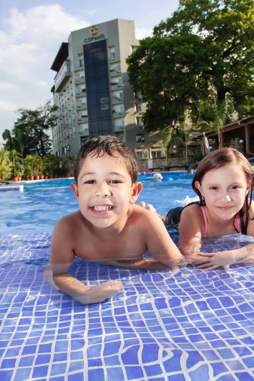 a boy and a girl laying in a swimming pool at Copantl Hotel & Convention Center in San Pedro Sula