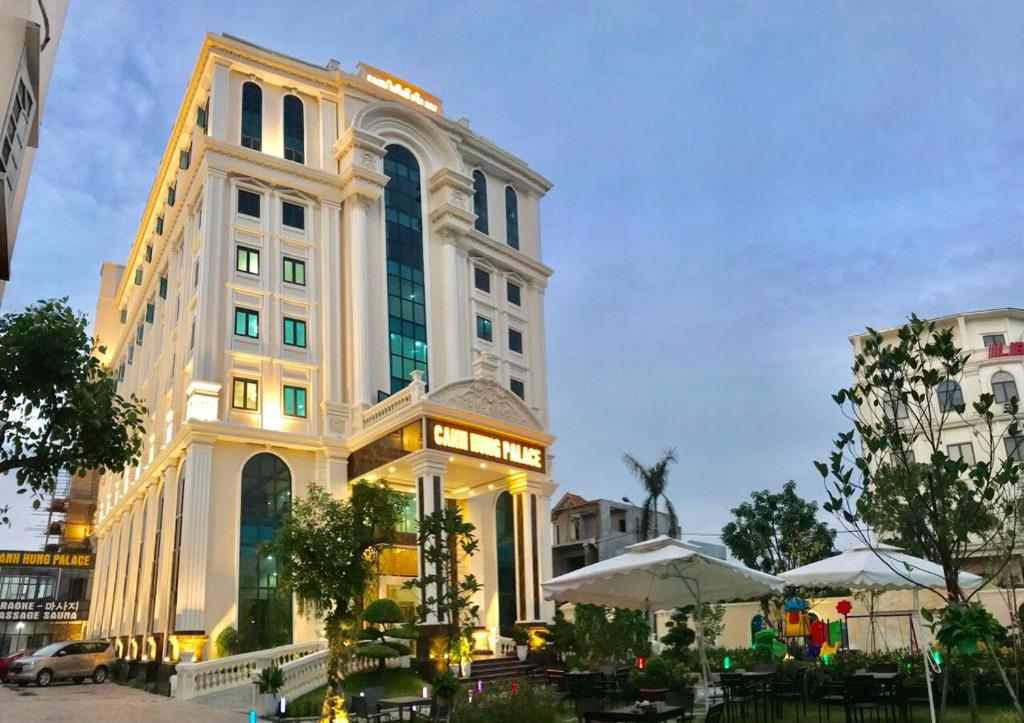 un gran edificio con mesas y sombrillas delante en Golden Palace Hotel en Hai Phong