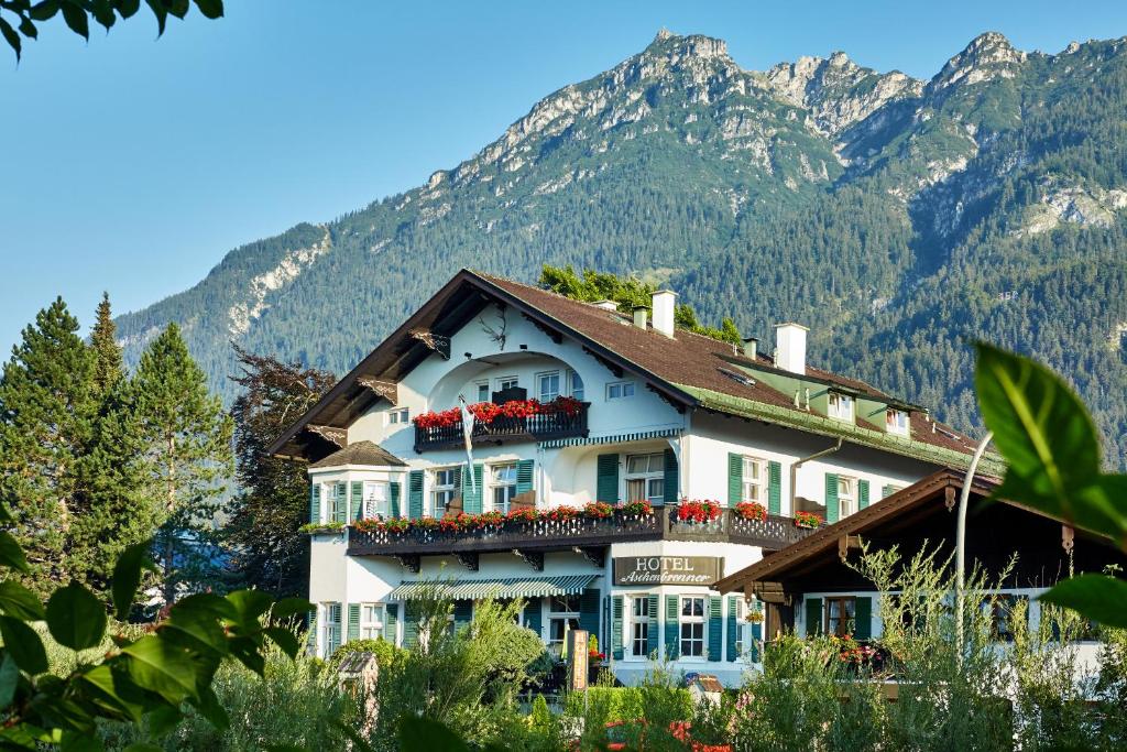 een gebouw met bloemen op de balkons voor de bergen bij Hotel Aschenbrenner in Garmisch-Partenkirchen