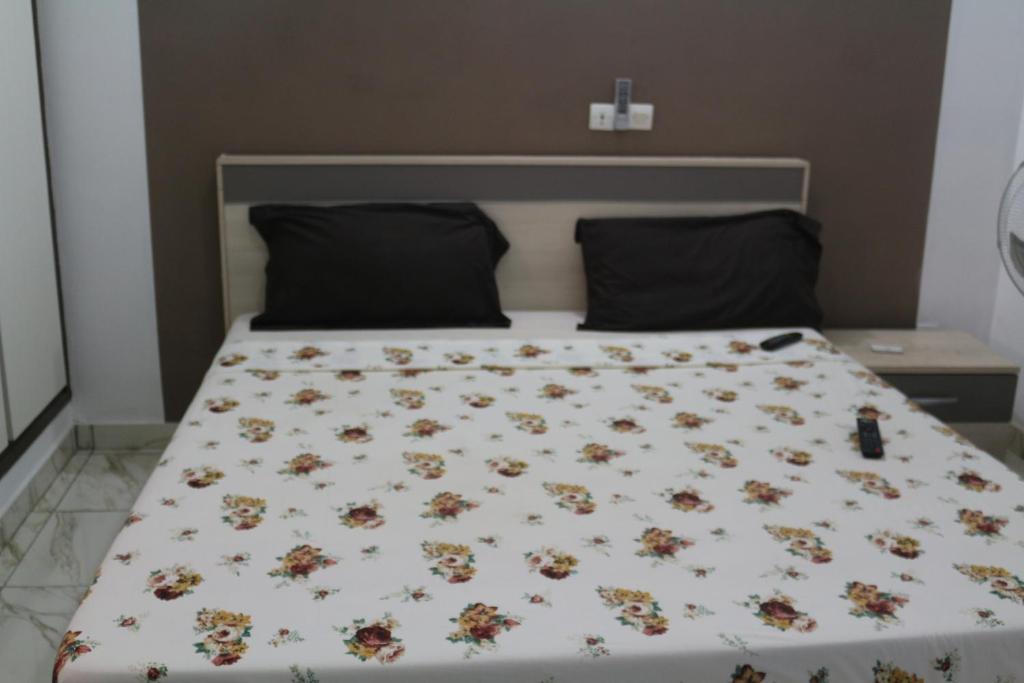 uma cama com uma colcha branca com flores em Happy Welcome Bietry 2 em Abidjan