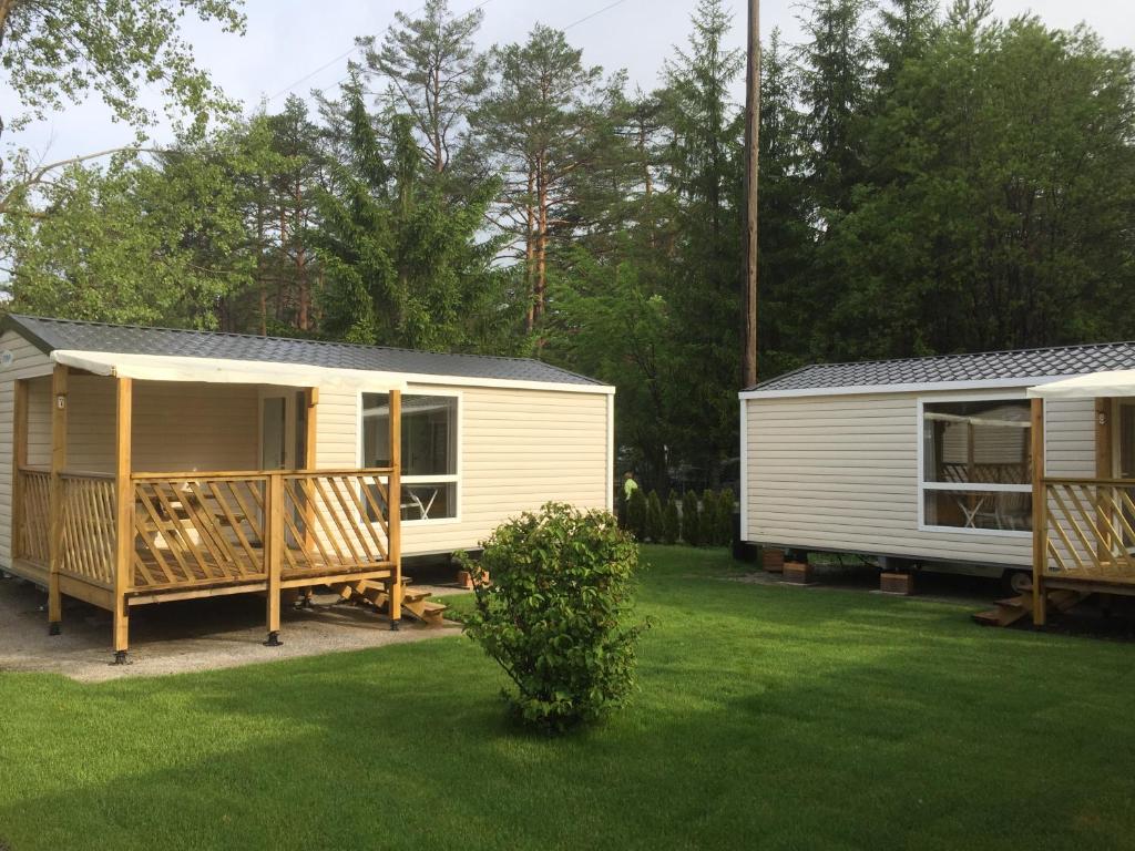 a white caravan with a porch and a house at Strandcamping Gruber in Faak am See