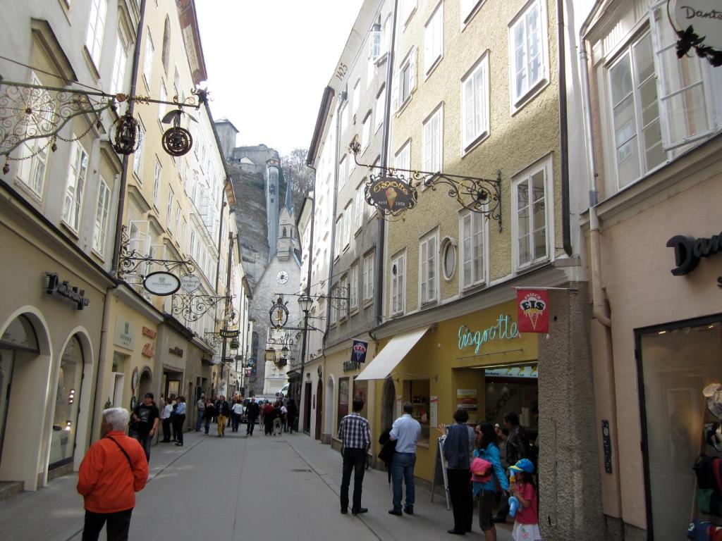 un gruppo di persone che camminano per una strada con edifici di City-Center Apartments a Salisburgo