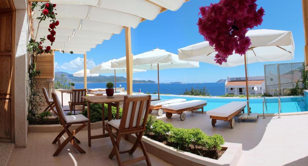 a patio with a table and chairs and umbrellas at Lycia Hotel in Kaş