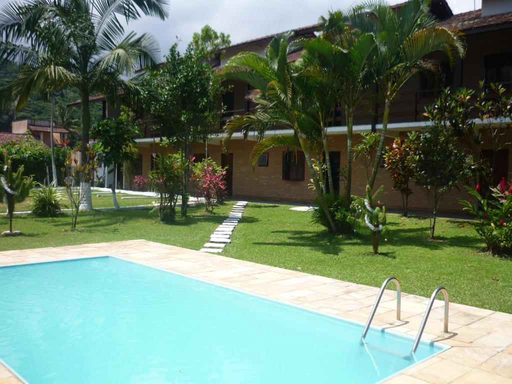 - une piscine en face d'une maison avec des palmiers dans l'établissement Chalés Santorini, à Caraguatatuba