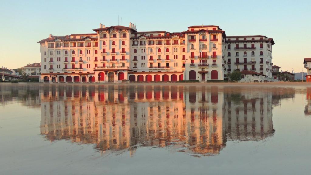 un grand bâtiment avec sa réflexion dans l'eau dans l'établissement Rêve d' Ocean Résidence Eskualduna b appt 113, à Hendaye