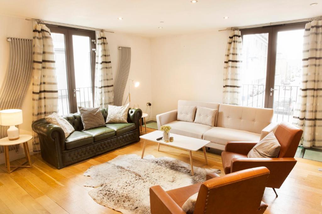 a living room with a couch and a table at The Holborn Lights - Modern 3BDR Home with Rooftop Terrace & Garage in London
