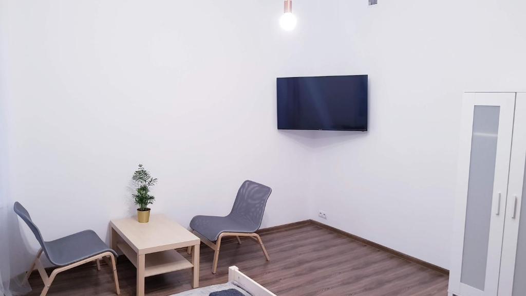 a living room with three chairs and a table and a tv at Guest Room RÓWNA in Kielce