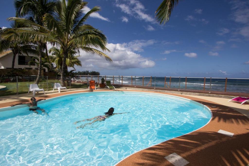 two people swimming in a swimming pool near the ocean at Leu Pied Dans L&#39;Eau in Saint-Leu