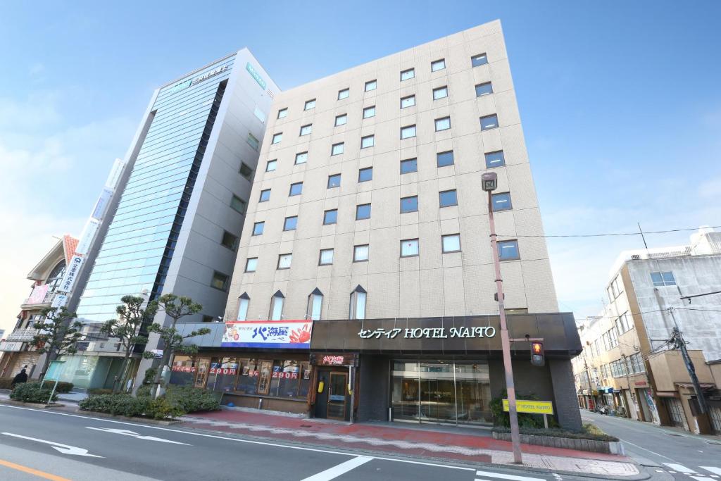 Un alto edificio bianco in una strada di città di Sentia Hotel Naito a Kōfu