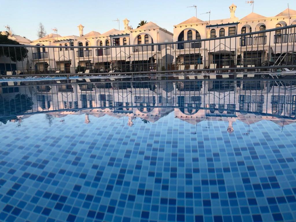 a pool in front of a building with blue tiles at Bungalow Playmar in Playa del Ingles