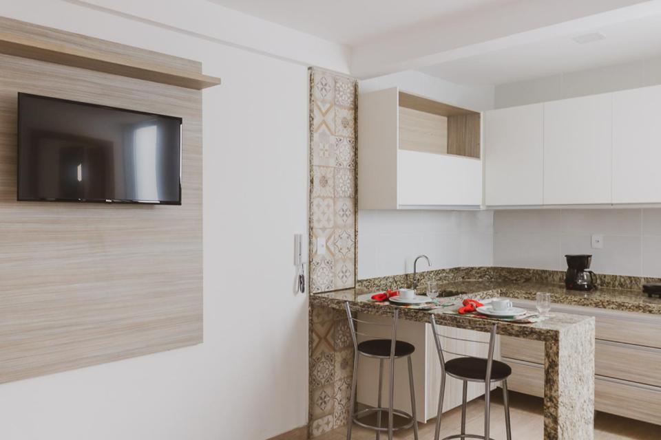 a kitchen with two bar stools and a counter at Star Apart Hotel in Teófilo Otoni