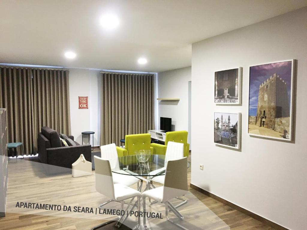 uma sala de estar com uma mesa de vidro e cadeiras amarelas em Apartamento da Seara "Douro" em Lamego