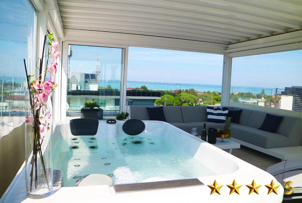 a bath tub in a living room with a large window at Hotel Rossini in Lignano Sabbiadoro