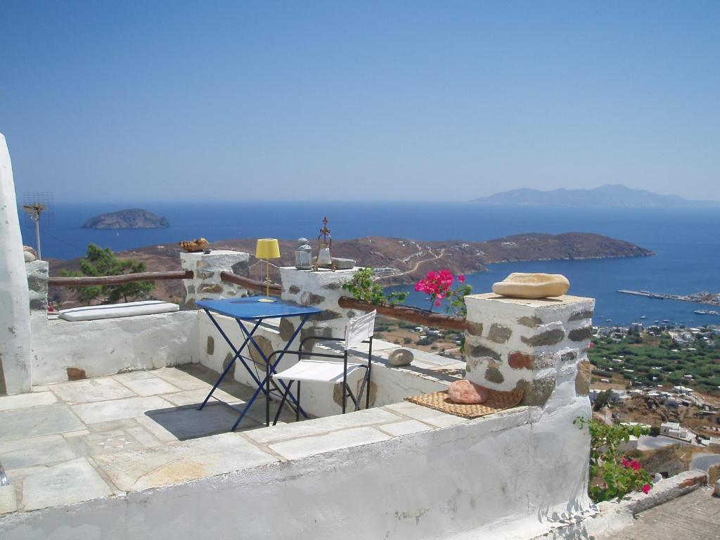 una mesa y sillas en un balcón con vistas al océano en Traditional stone house with breathtaking view, en Serifos Chora