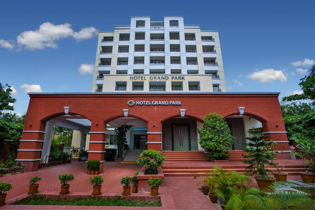 a red brick building with a tall building in the background at Hotel Grand Park Barishal in Barisāl