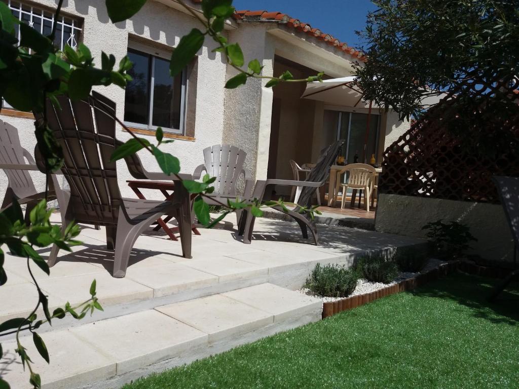 a pair of chairs sitting in the yard of a house at Belle villa classée 4 étoiles proche plage avec jardin in Saint Cyprien Plage