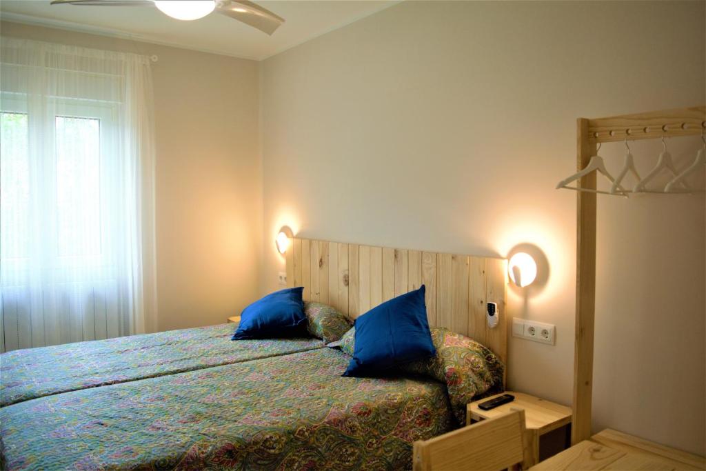 Un dormitorio con una cama con almohadas azules y una ventana en B&B LOS LLANOS en Estella