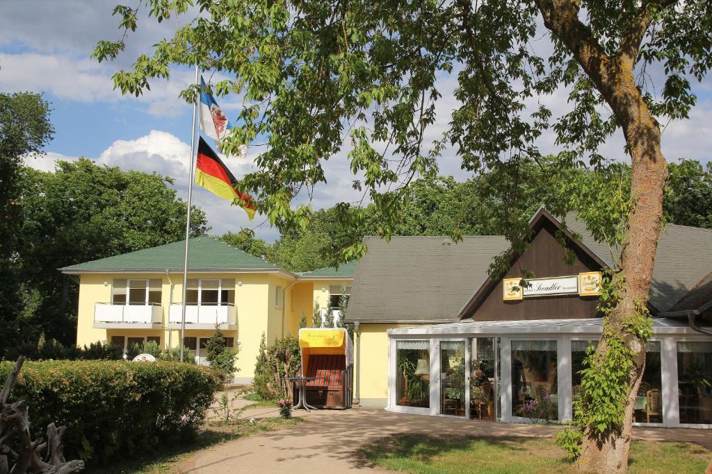 a flag flying in front of a yellow building at Hotel Seeadler in Zempin