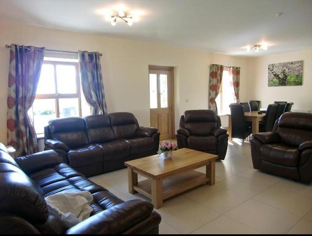 sala de estar con sofás de cuero y mesa de centro en Caherush Lodge, en Quilty
