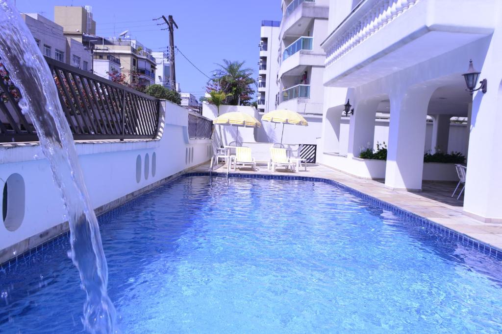 uma piscina com uma fonte de água num edifício em Ap Enseada Lado Praia Ar Cond Piscina Wi-Fi 500Mb no Guarujá
