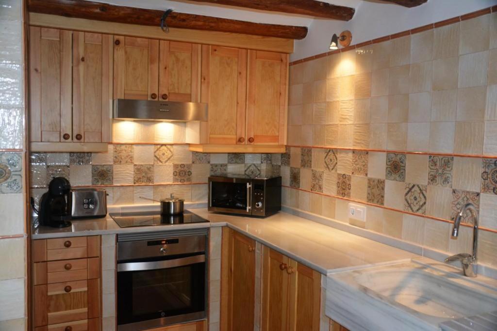 a kitchen with wooden cabinets and a stove top oven at Cal Triquell in El Vilosell