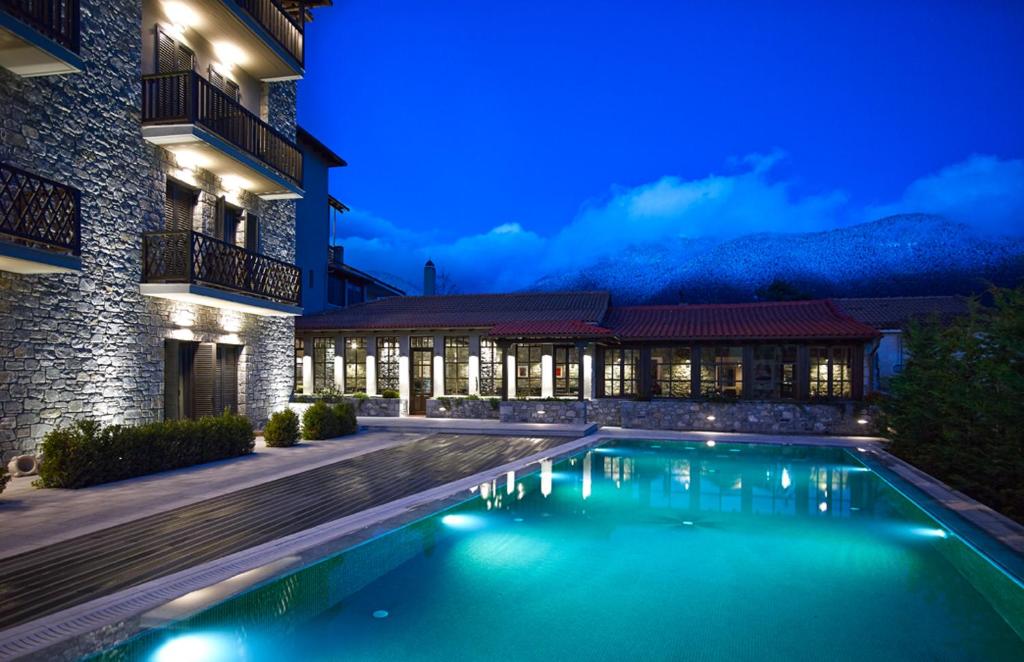 una piscina frente a un edificio por la noche en Art Mainalon Hotel en Vytina