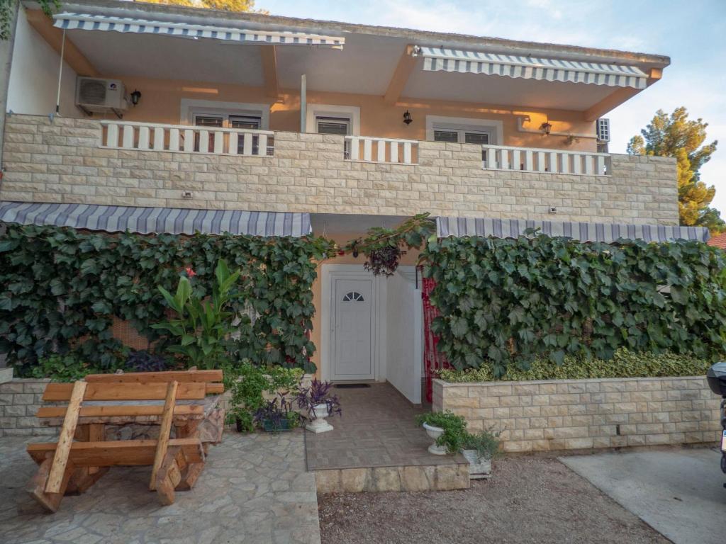 une maison en briques avec une haie verte dans l'établissement Apartments Plaža, à Ivan Dolac