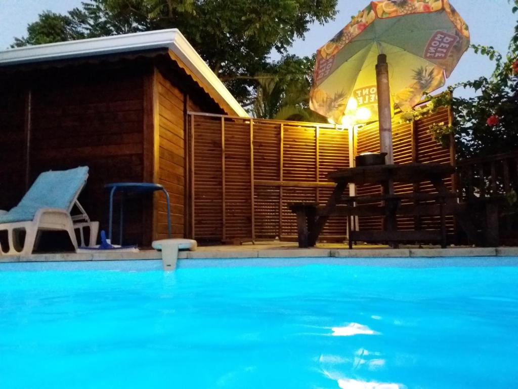 a house with an umbrella and a swimming pool at mon Ecolodge Creole in Fort-de-France
