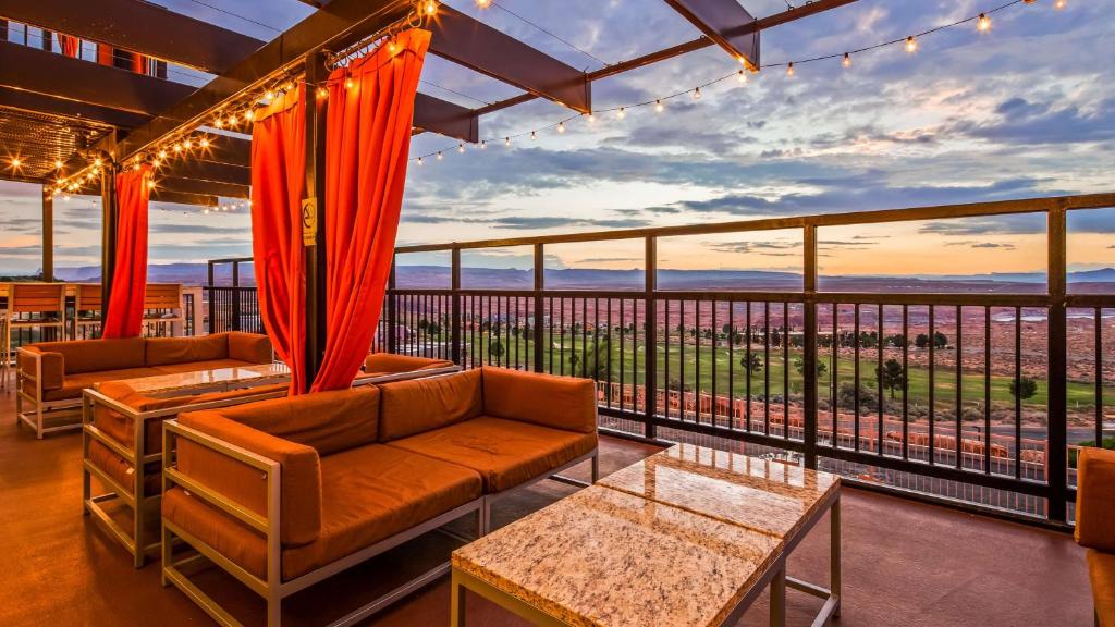 Best Western View of Lake Powell Hotel في بيج: غرفة معيشة مع كنب وشرفة مطلة