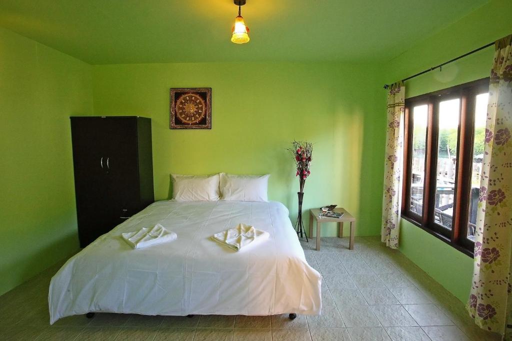 a green bedroom with a bed with two towels on it at PP Red Tuna Hut in Phi Phi Don