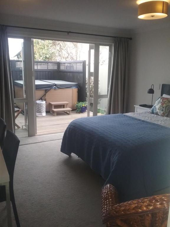 a bedroom with a bed and a door to a deck at Alfred's@115 in Blenheim