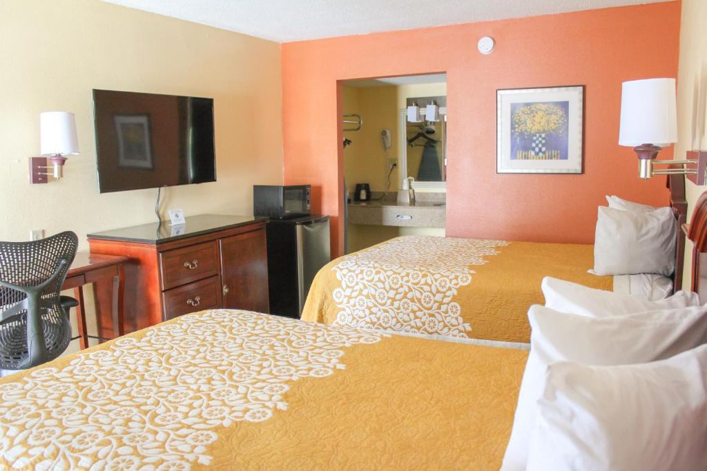 a hotel room with two beds and a television at Rose Garden Inn & Suites Thomasville in Thomasville