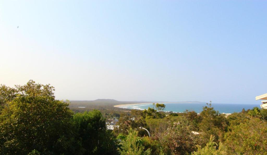 a view of a beach and the ocean from a hill at Barefoot, 32 Skyline Crescent, Crescent Head in Crescent Head