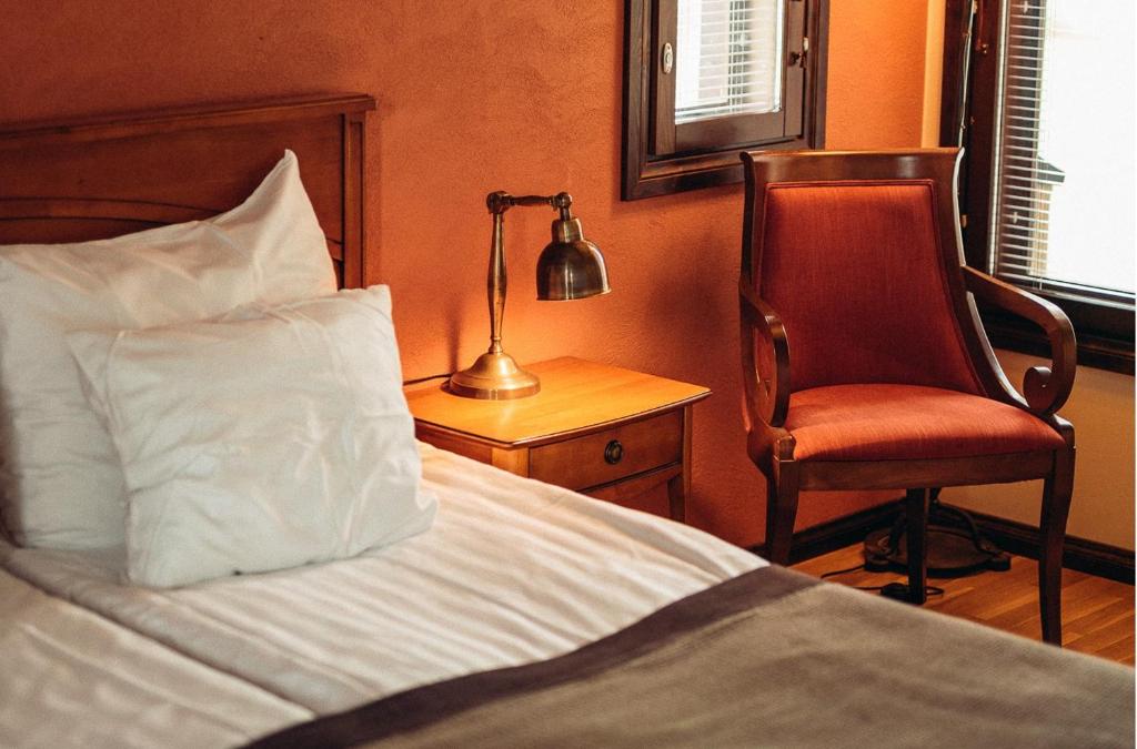 a bedroom with a bed and a chair and a lamp at Tahko Golden Resort in Tahkovuori