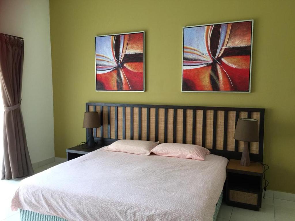 um quarto com uma cama e duas pinturas na parede em Happy Stay @ Morib Gold Coast em Banting