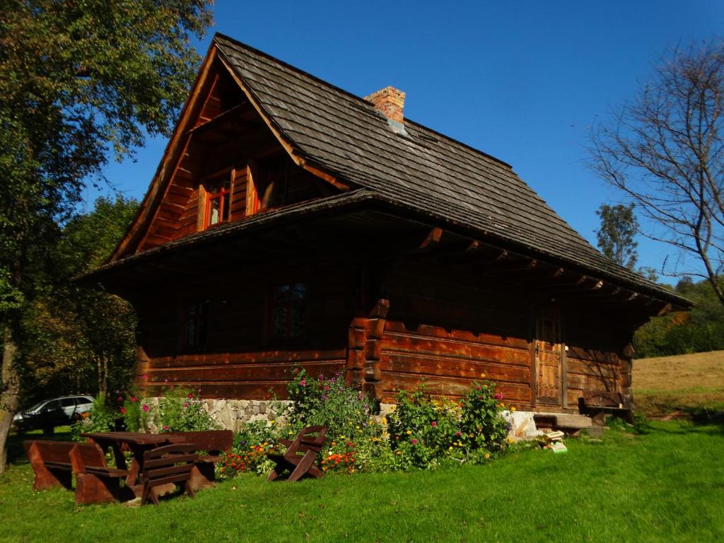 eine Blockhütte mit einem schwarzen Dach im Gras in der Unterkunft Domek U Leny in Polana