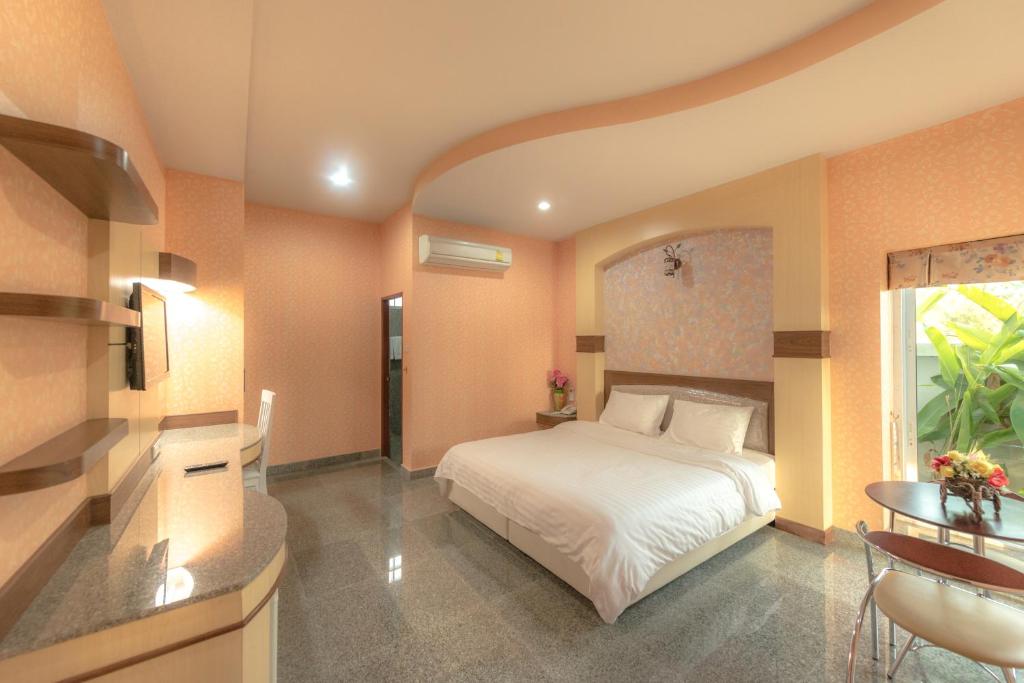 1 dormitorio con cama blanca y mesa en Martina Hotel Surin en Surin