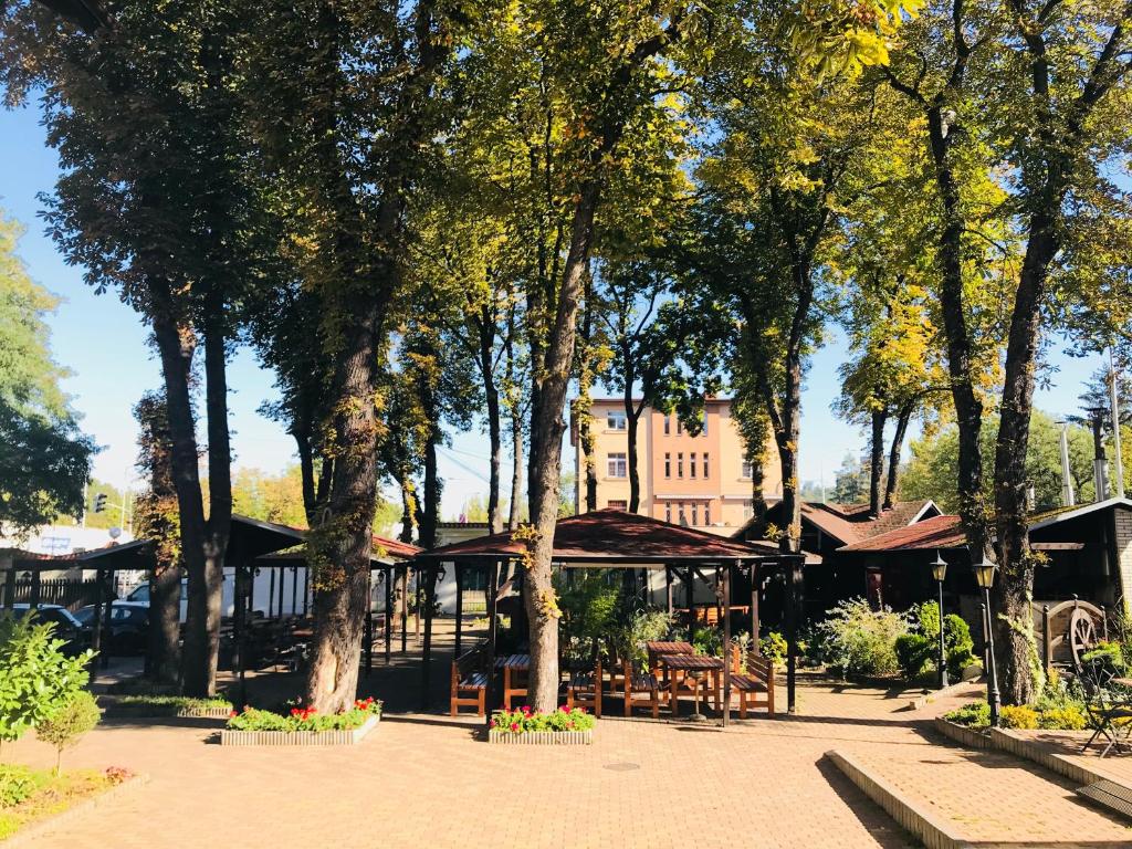 فندق Braník في براغ: حديقة فيها اشجار وكراسي ومبنى