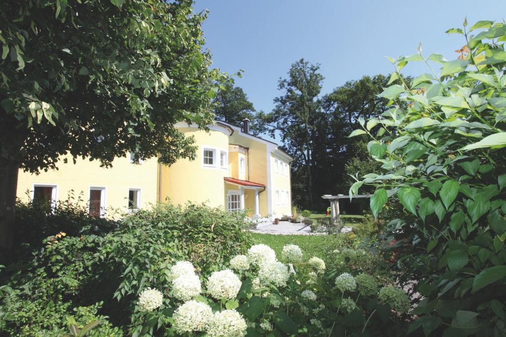 un jardin avec des fleurs blanches devant une maison jaune dans l'établissement Haus Hildegunde, à Bad Füssing