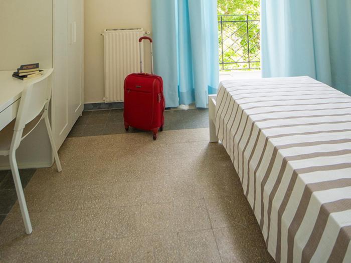 a room with a bed and a red suitcase at Ostello San Luigi Orione in Anzio