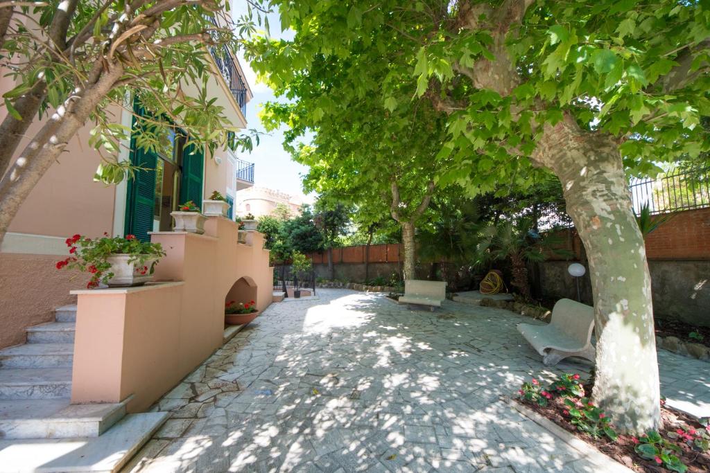 a walkway with a tree and a chair next to a building at Ostello San Luigi Orione in Anzio