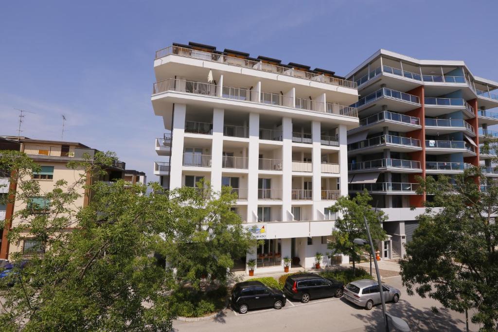 a white building with cars parked in front of it at Hotel Eldorado, Depandance & Apartments in Grado