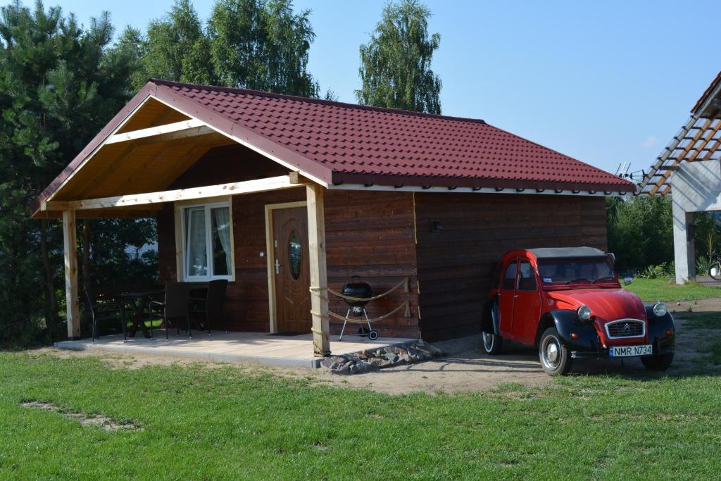 um pequeno barracão com um camião vermelho estacionado nele em RÓŻANY ZAKĄTEK em Zełwągi