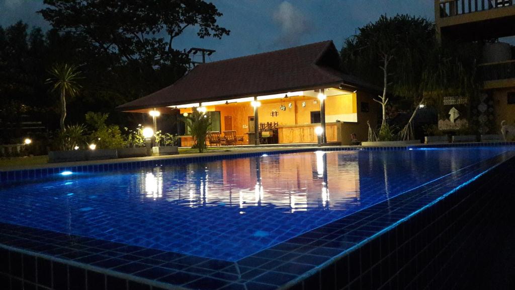 a swimming pool in front of a building at night at Raintree Bangsak in Khao Lak
