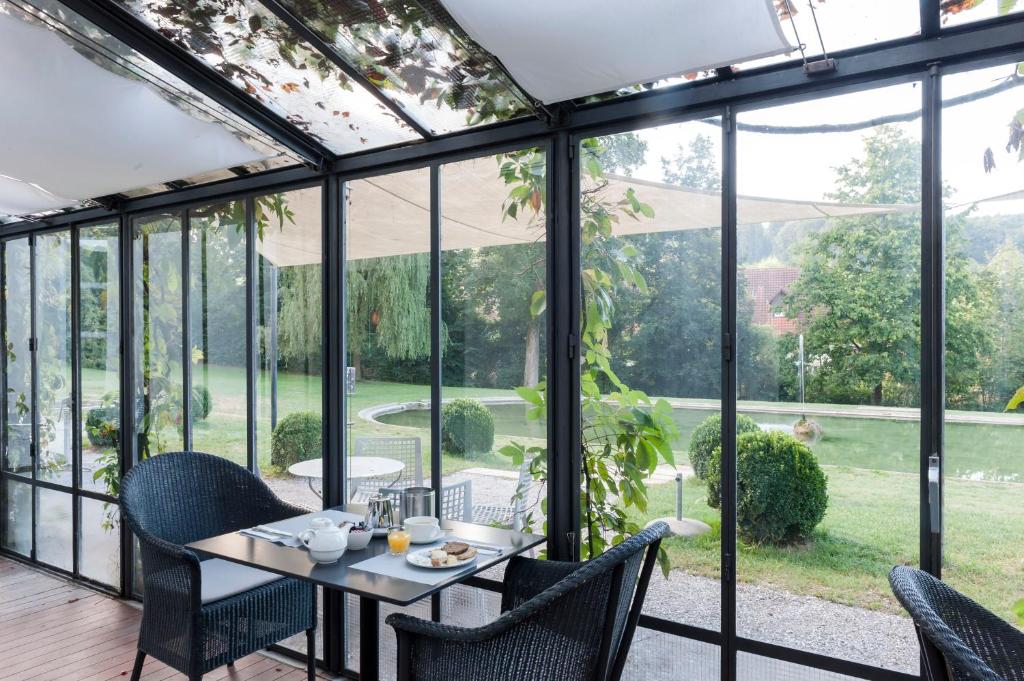 a conservatory with a table and chairs and glass doors at Schloss Münchenwiler in Murten