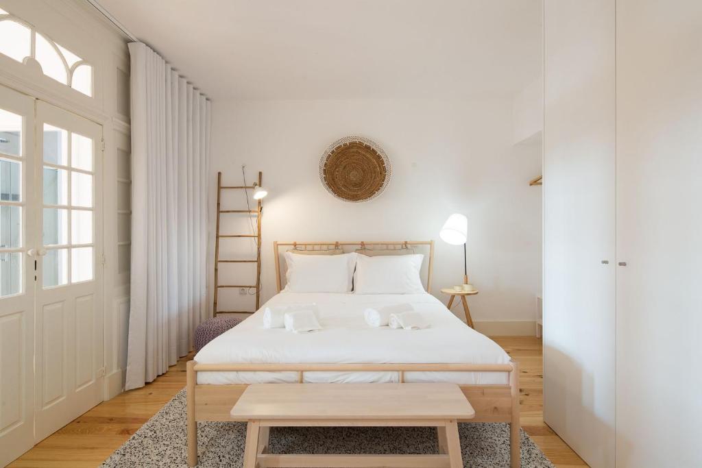 ein weißes Schlafzimmer mit einem Bett und einem Tisch in der Unterkunft LovelyStay - Martires Boutique Flat in Porto