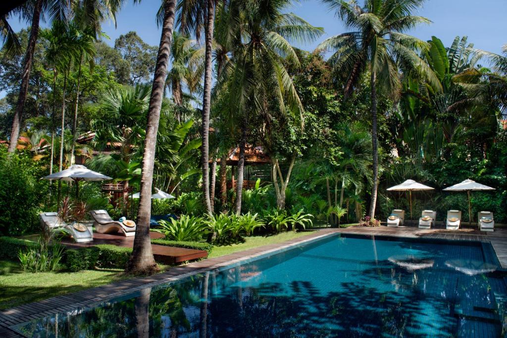 a swimming pool in front of a resort with palm trees at Maison Polanka in Siem Reap
